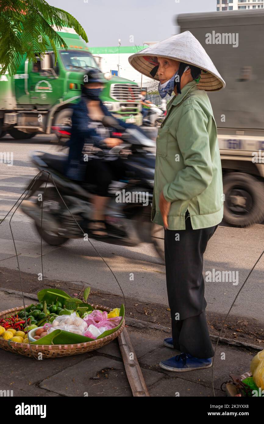 Vendedor ambulante vietnamita usando sombrero de bambú vendiendo comida de pannier en la calle, Hai Phong, Vietnam Foto de stock
