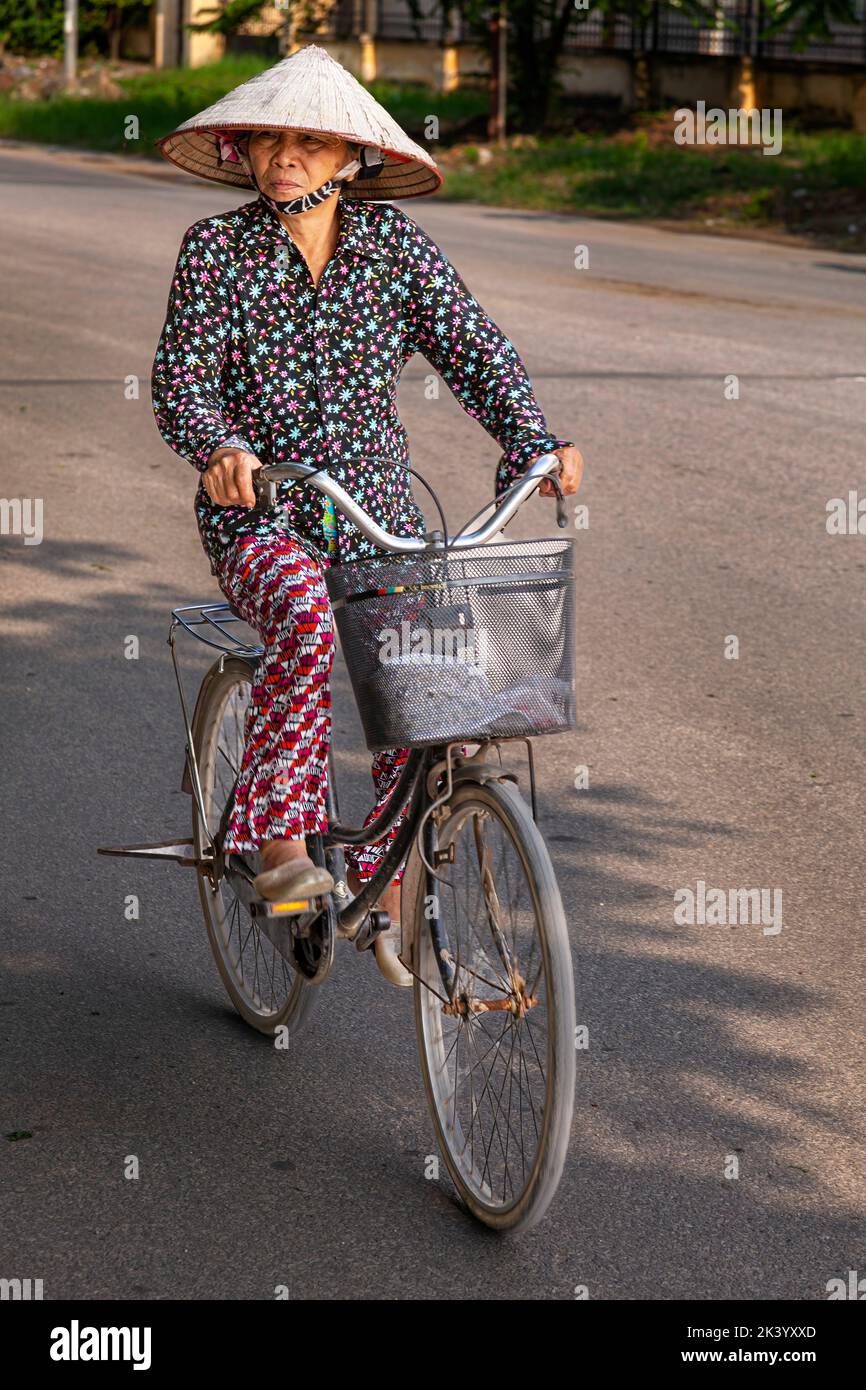 Mujer vietnamita usando sombrero cónico de bambú, con bicicleta, Hai Phong, Vietnam Foto de stock