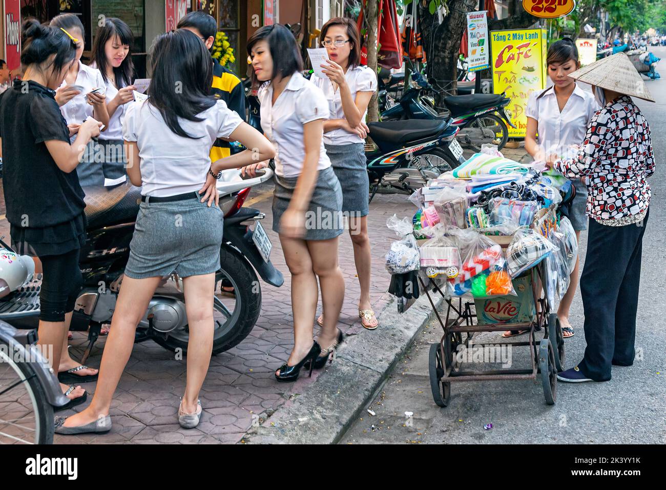Joven estudiante vietnamita en uniforme con vendedores ambulantes, Hai Phong, Vietnam Foto de stock