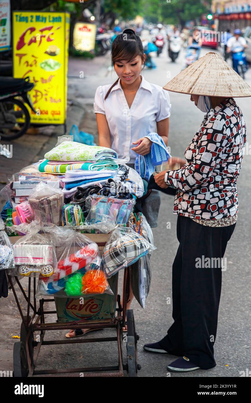 Joven estudiante vietnamita en uniforme con vendedores ambulantes, Hai Phong, Vietnam Foto de stock