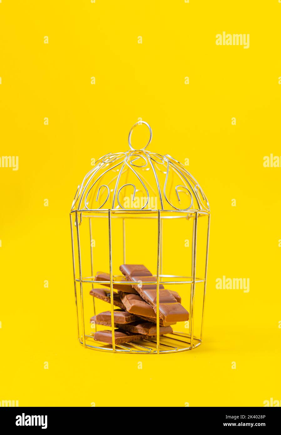 Trozos de chocolate encerrados en una jaula. Concepto de motivación Foto de stock