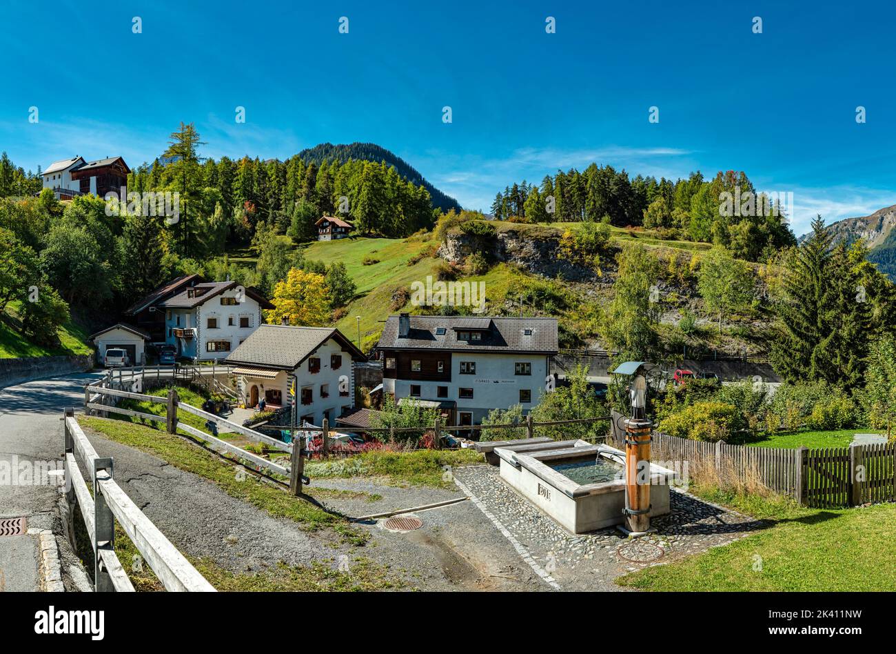 Una fuente de agua con una estatua sagrada *** Título Local *** Tarasp - Scuol, Graubünden, Suiza, ciudad, pueblo, campo, pradera, árboles, otoño, mounta Foto de stock