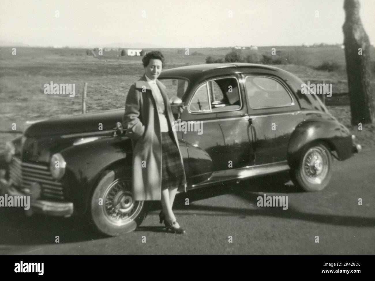 Mujer con un coche a lo largo de la carretera, Italia 1940s Foto de stock