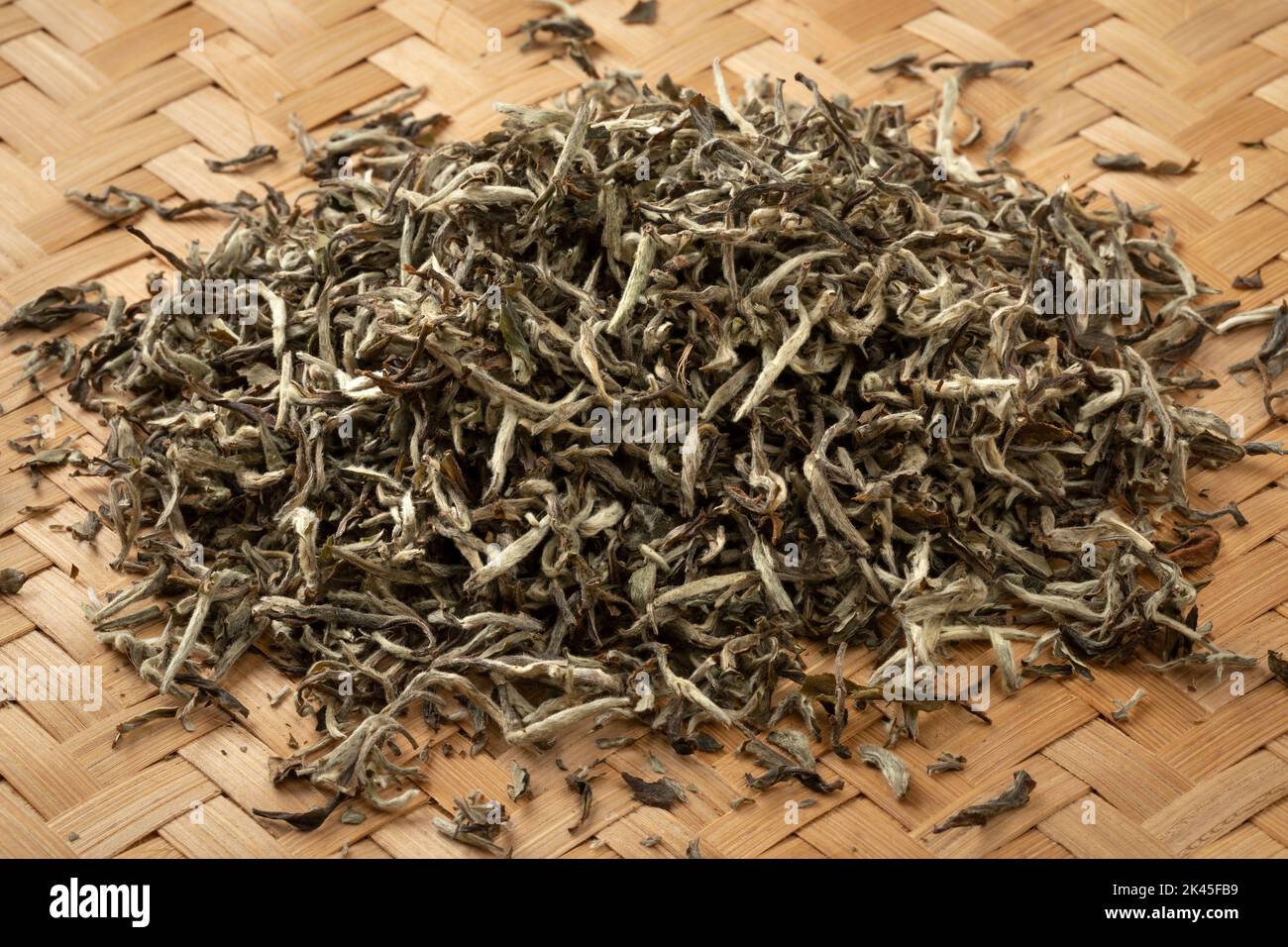 Montón de hojas secas de té de naranja blanca nepalesa de cerca en una estera de mimbre Foto de stock