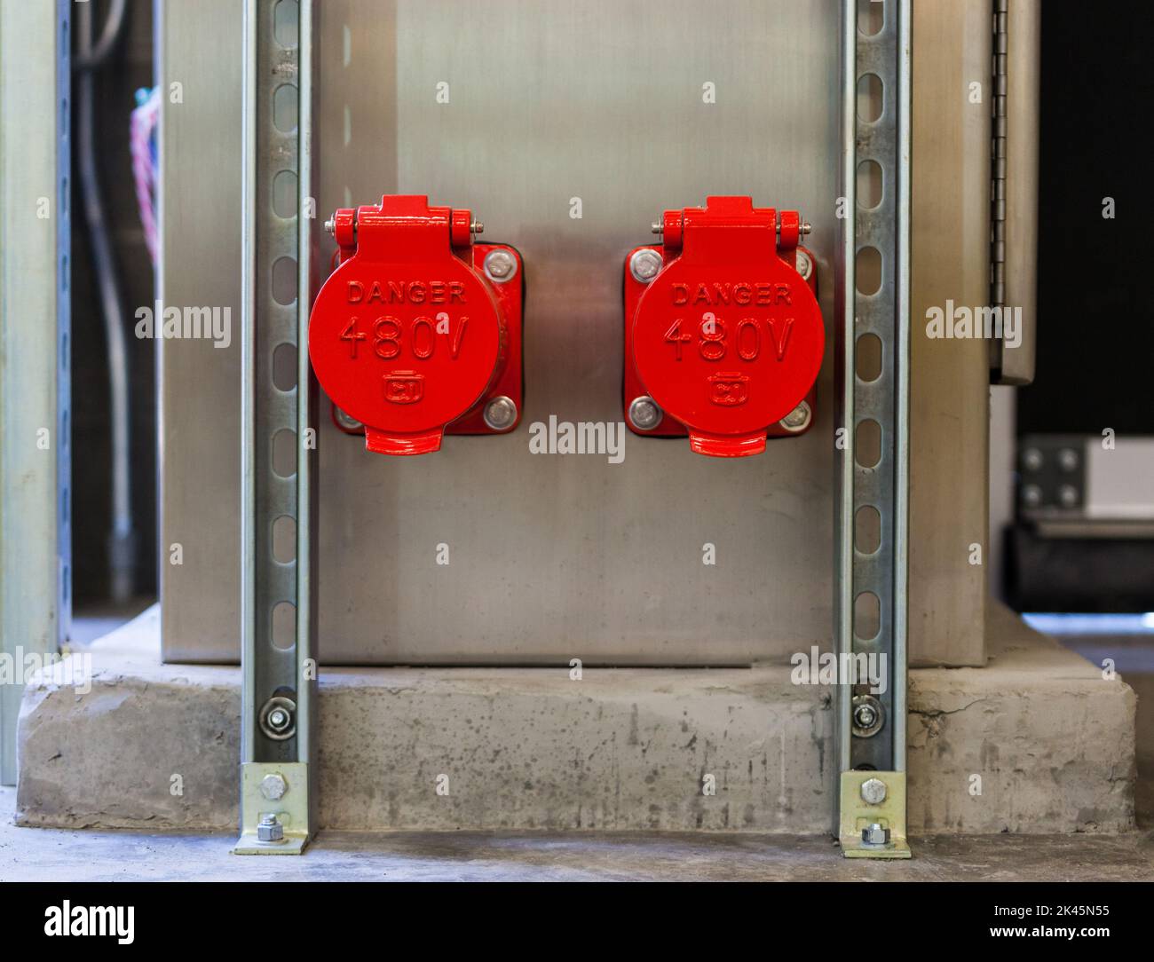 Dos cubiertas de plástico rojo brillante, tapas que cubren puntos de energía eléctrica en una pared Foto de stock