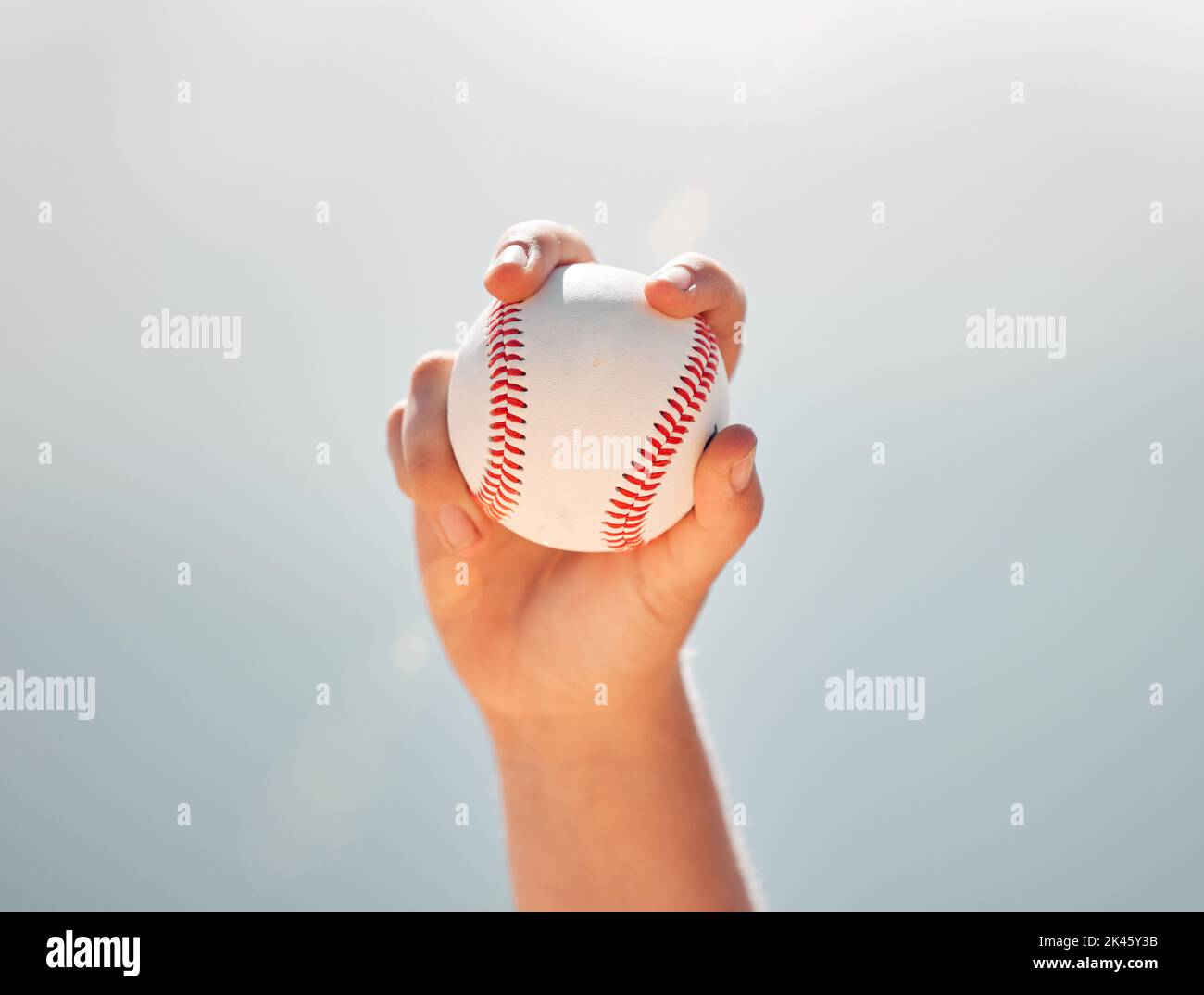 Béisbol, manos de atleta y deportes de pelota mientras que muestra el agarre de la jarra contra un cielo azul claro. Ejercicio, juego y softbol con un jugador profesional Foto de stock