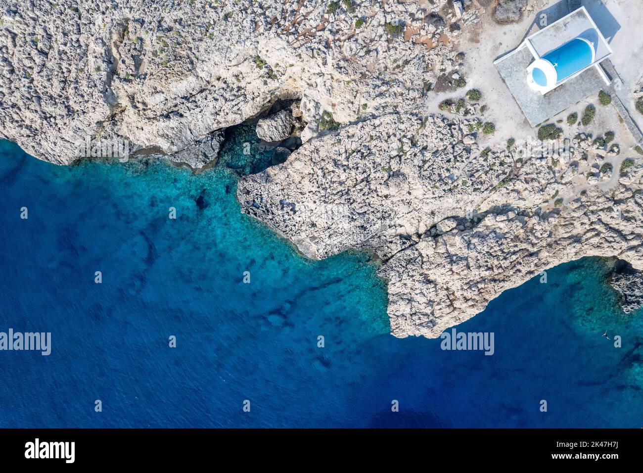 Fotografía aérea de aviones teledirigidos de la península de Cabo Greco con la iglesia Agioi Anargyroi en las rocas. Agua turquesa del océano Foto de stock