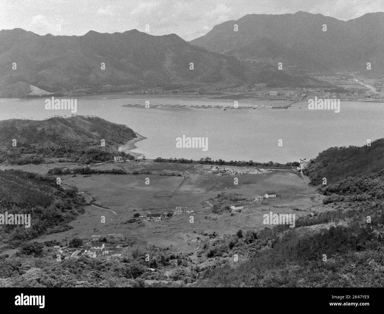 Vista en Blanco y Negro de la Escuela Kuk Po, (centro izquierda), y Kuk Po Marsh, - Sha Tau Kok al otro lado del agua, noreste de los Nuevos Territorios, Hong Kong 1984 Foto de stock