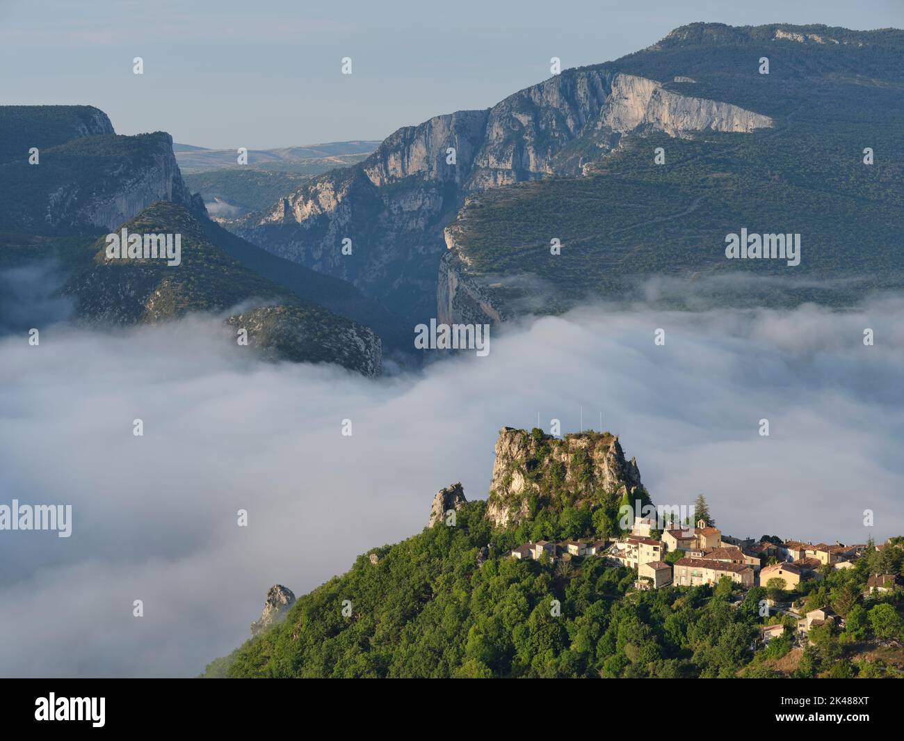Pueblo medieval encaramado por encima de la niebla de la mañana con los enormes acantilados de la Garganta de Verdon para el fondo. Rougon, Alpes de Haute-Provence, Francia. Foto de stock
