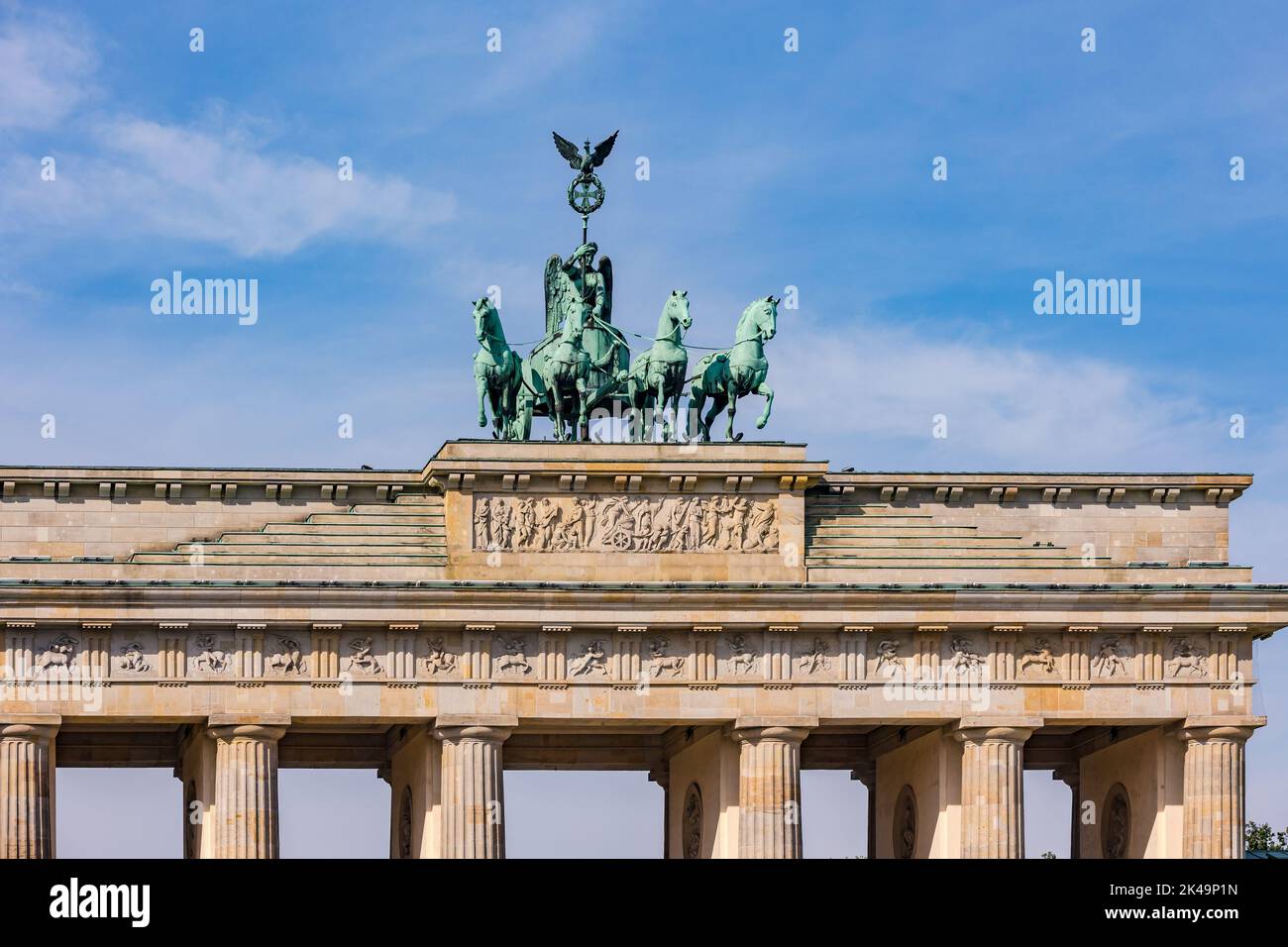 El equipo de caballos de la Quadriga en la Puerta de Brandenburgo en Berlín contra el cielo azul es un símbolo nacional de la unidad alemana Foto de stock