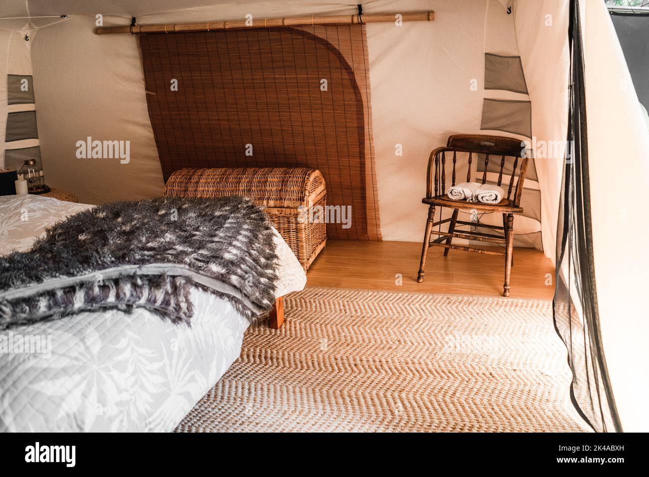 bonita habitación cómoda en una tienda con un gran tronco de mimbre y una vieja mesa de madera con dos toallas enrolladas Foto de stock