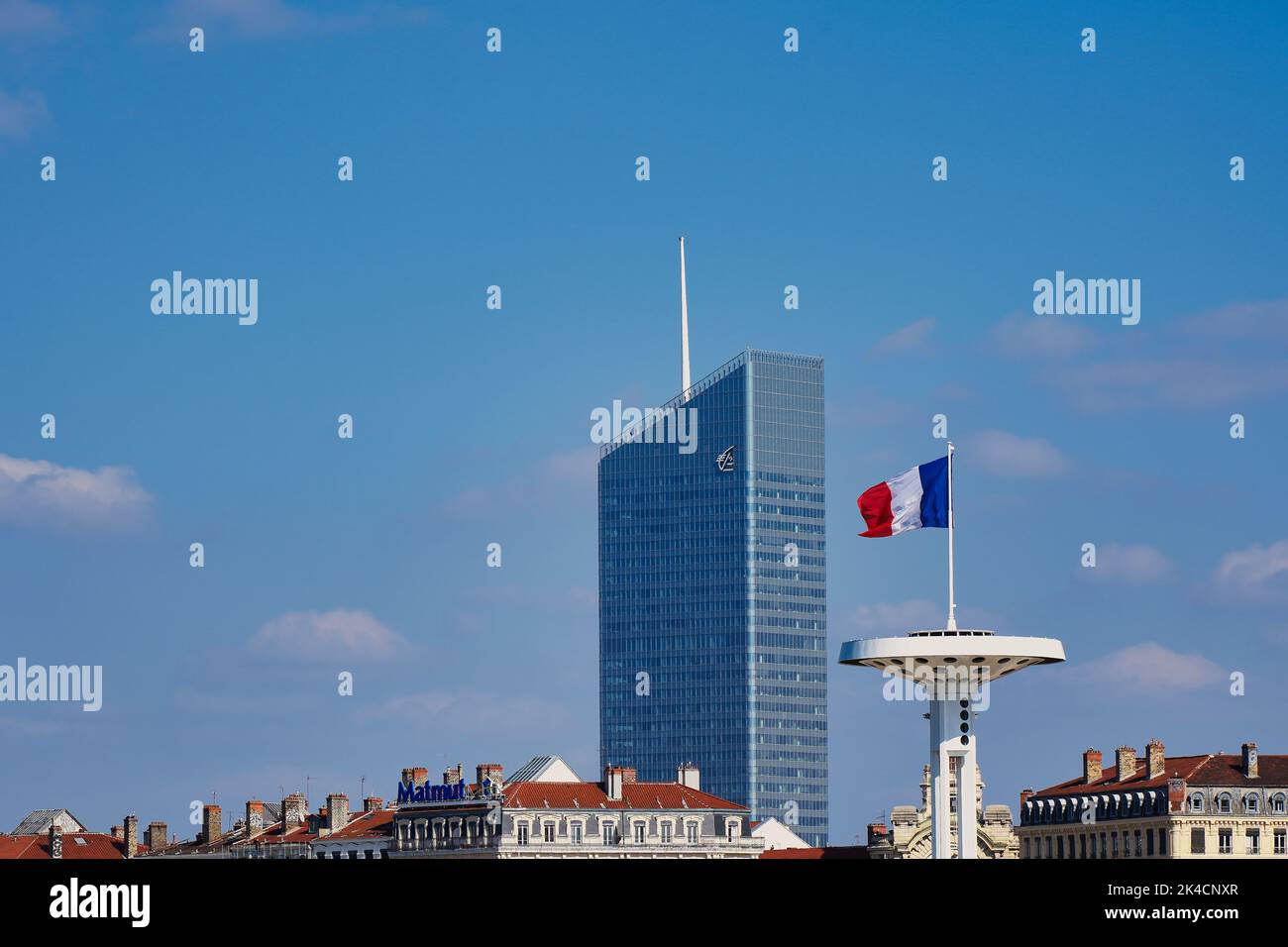 Una hermosa vista de la Torre InCity, Caisse d'Epargne en Lyon, Francia con la bandera francesa bajo un cielo nublado pálido Foto de stock