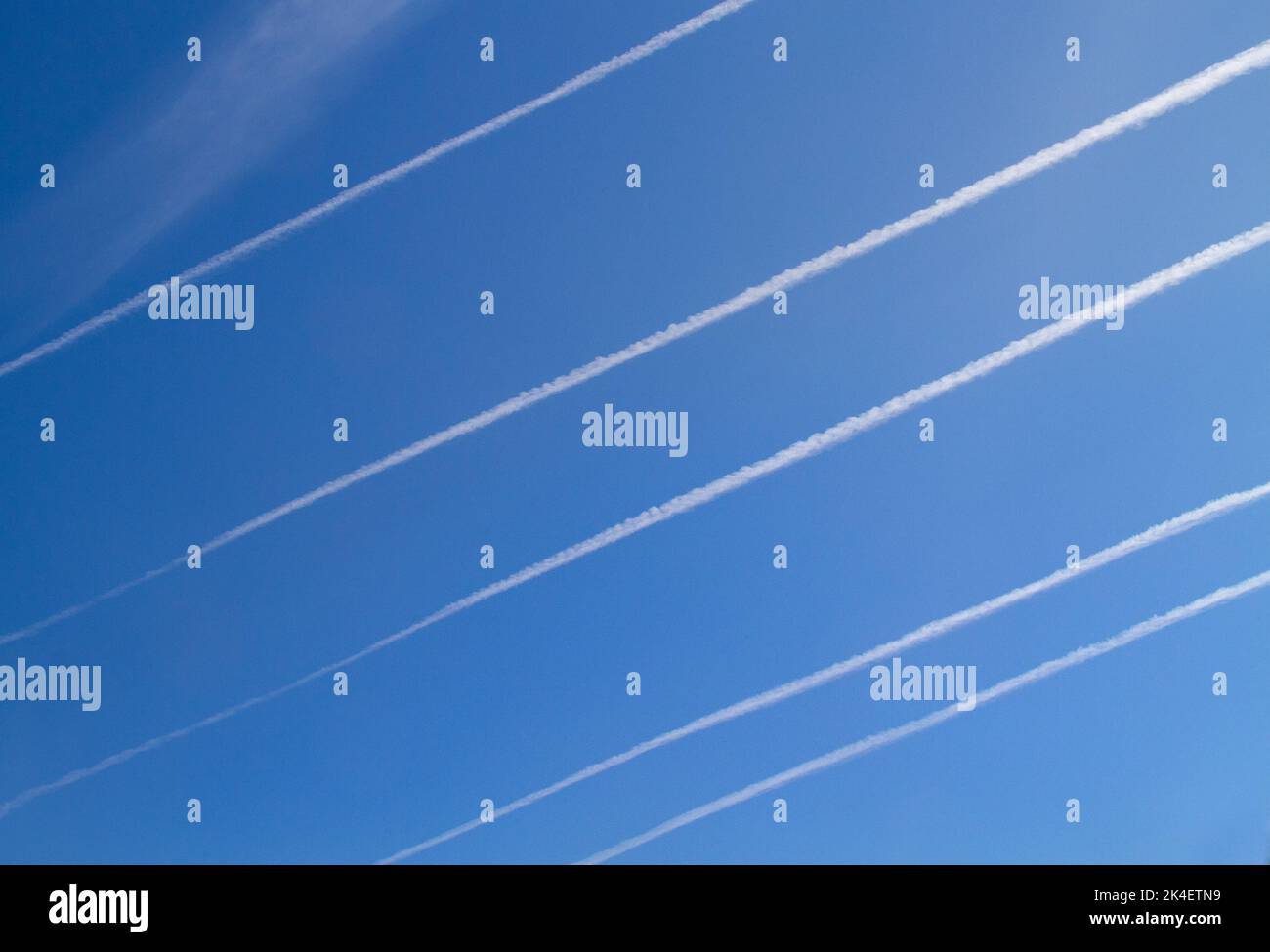 Cinco pistas paralelas de condensación, estelas de vapor o estelas de vapor en un cielo azul Foto de stock
