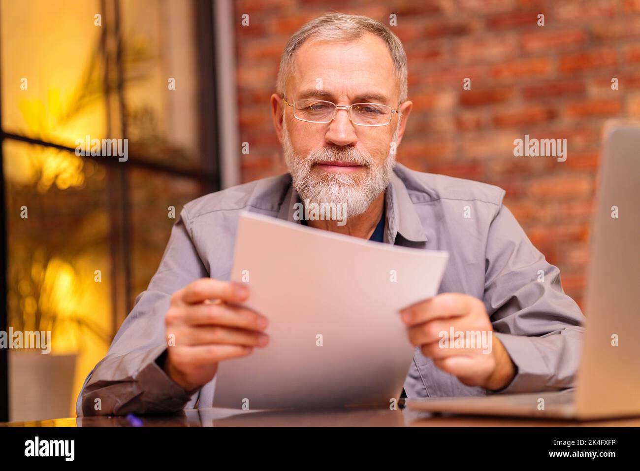 un anciano preocupado se sienta en el ordenador portátil e intente hacer el pago en línea Foto de stock