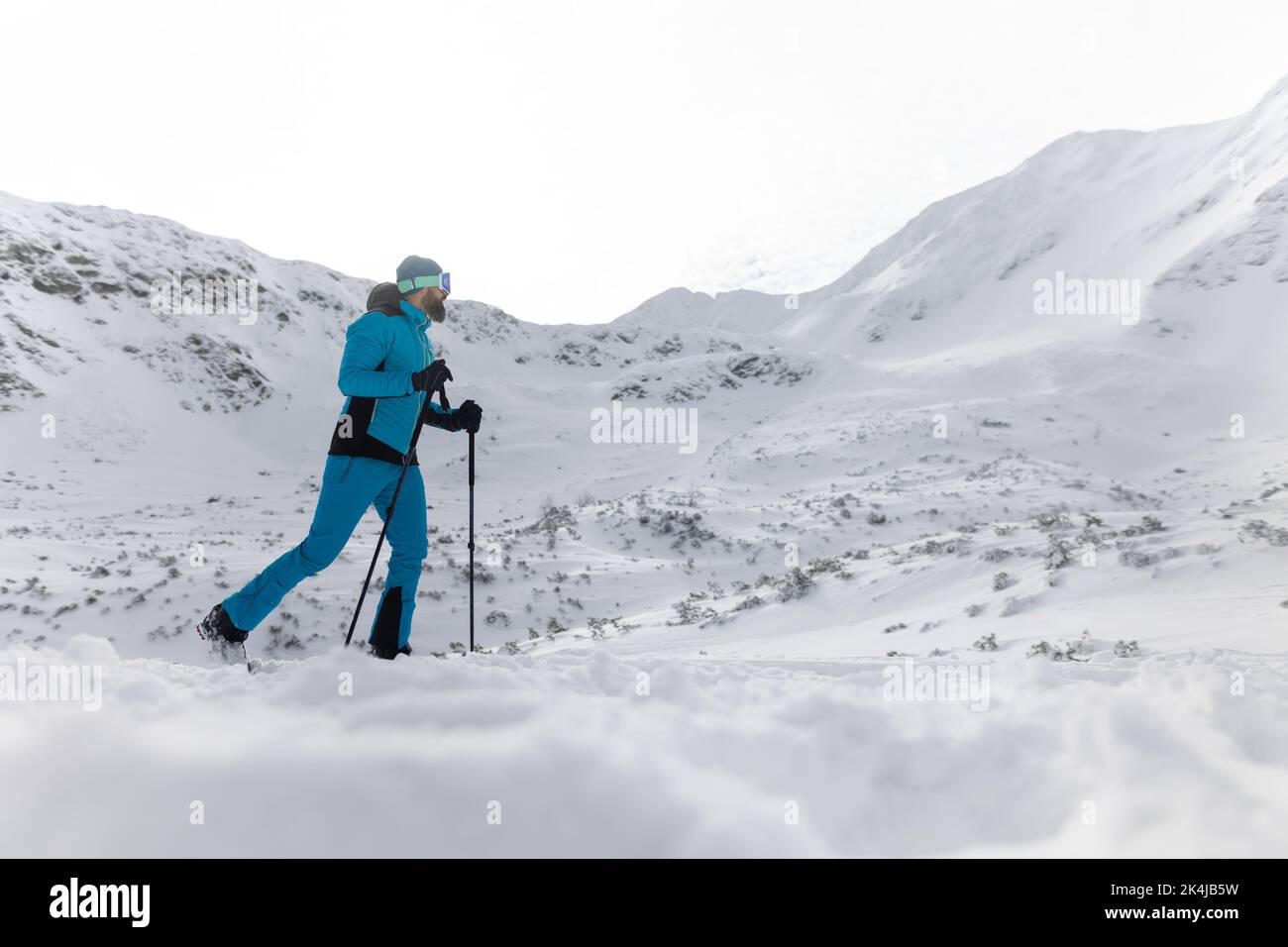 Hombre esquiador de campo a pie hasta la cumbre de un pico nevado en el Bajo Tatras en Eslovaquia. Foto de stock