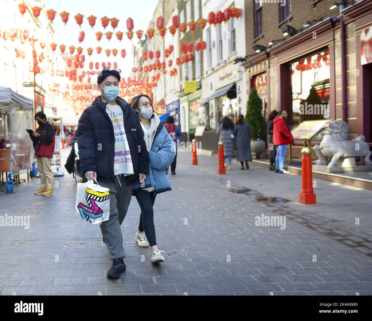 Londres, Inglaterra, Reino Unido. Joven pareja china en Chinatown usando máscaras faciales durante la pandemia de COVID, marzo de 2022 Foto de stock