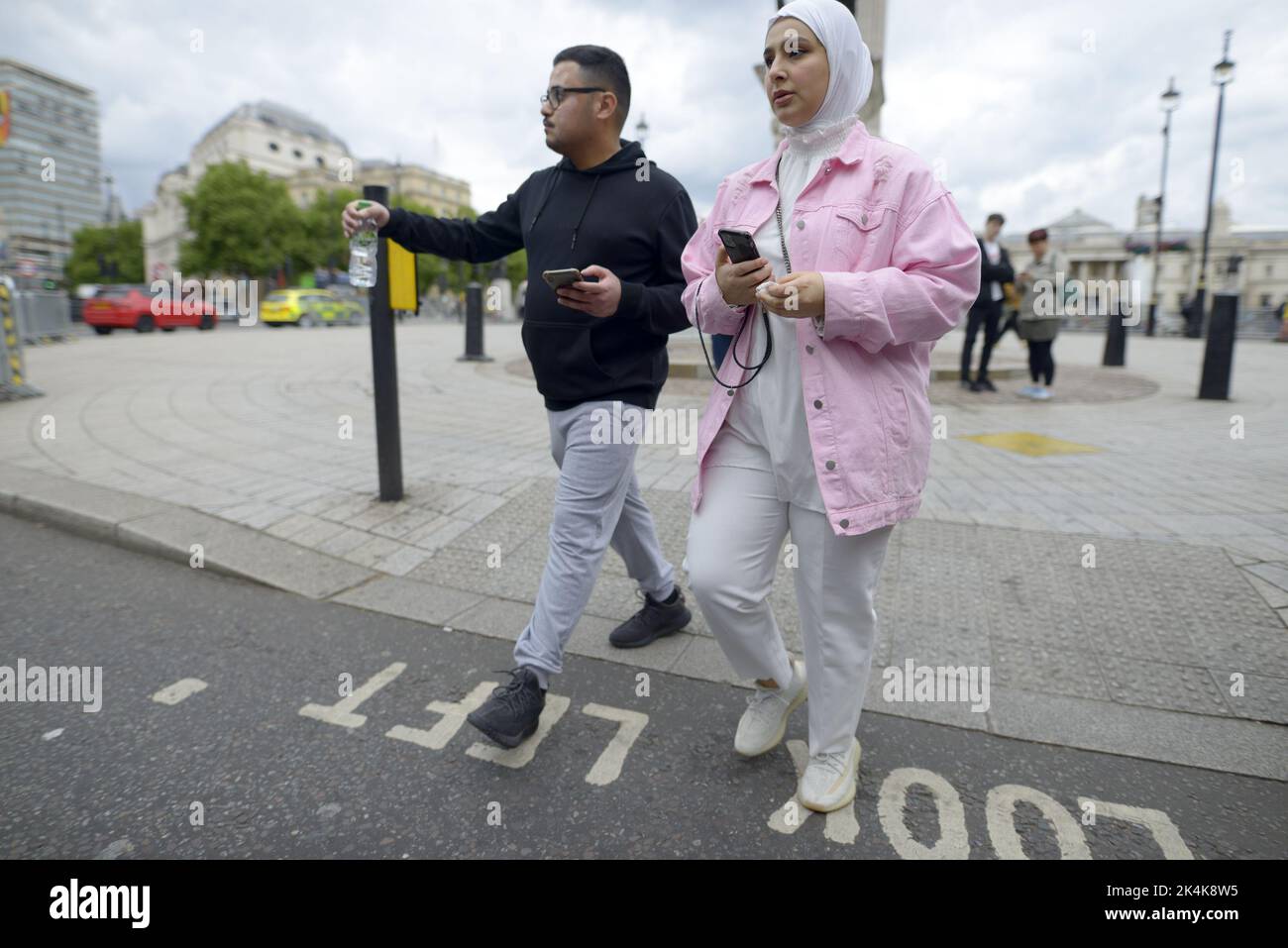 Londres, Inglaterra, Reino Unido. Joven musulmana con un teléfono móvil en Trafalgar Square Foto de stock