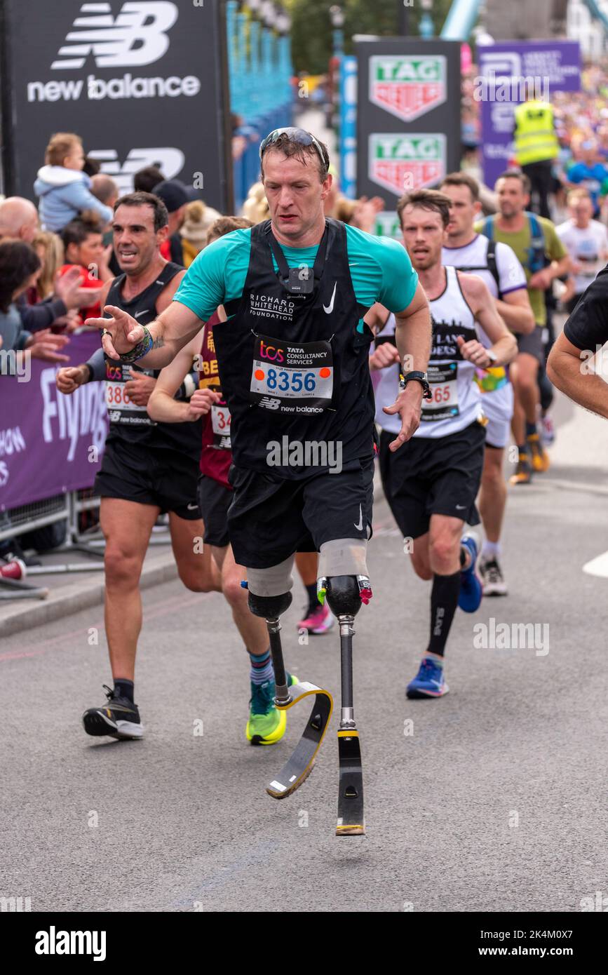 Correr en el TCS London Marathon 2022, en la carretera de aproximación Tower Bridge, City of London, Reino Unido. Foto de stock