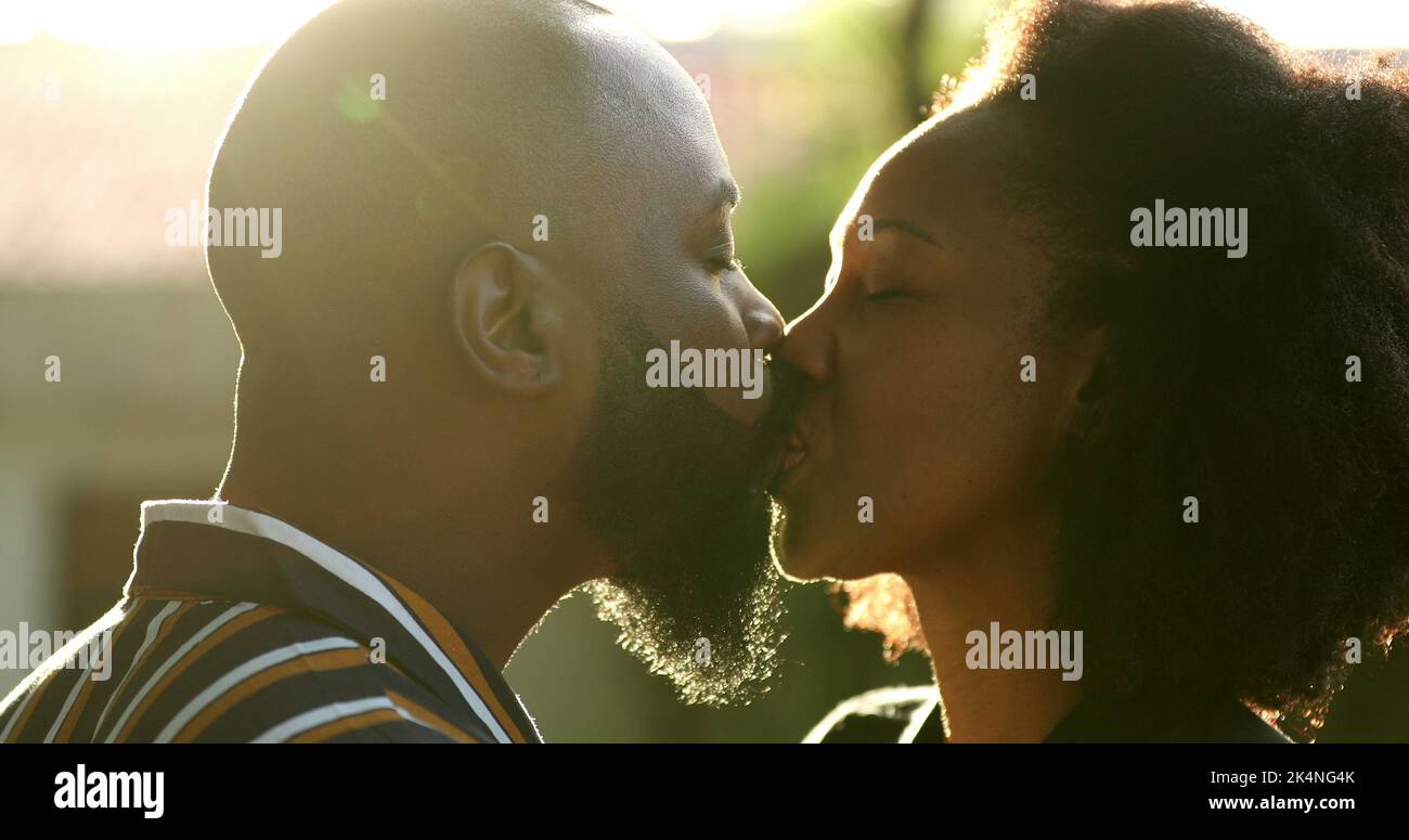 Hombre negro besando a su esposa fuera con la luz del sol lente-llamarada Foto