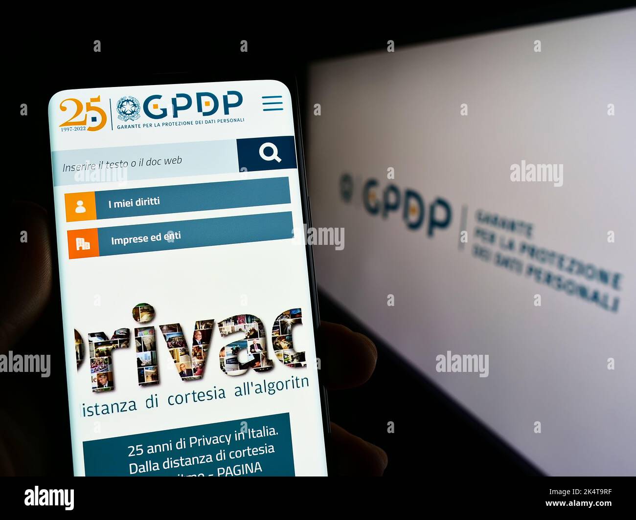 Persona que posee un teléfono móvil con el sitio web de la Autoridad Italiana de Protección de Datos (GPDP) en la pantalla delante del logotipo. Enfoque en el centro de la pantalla del teléfono. Foto de stock