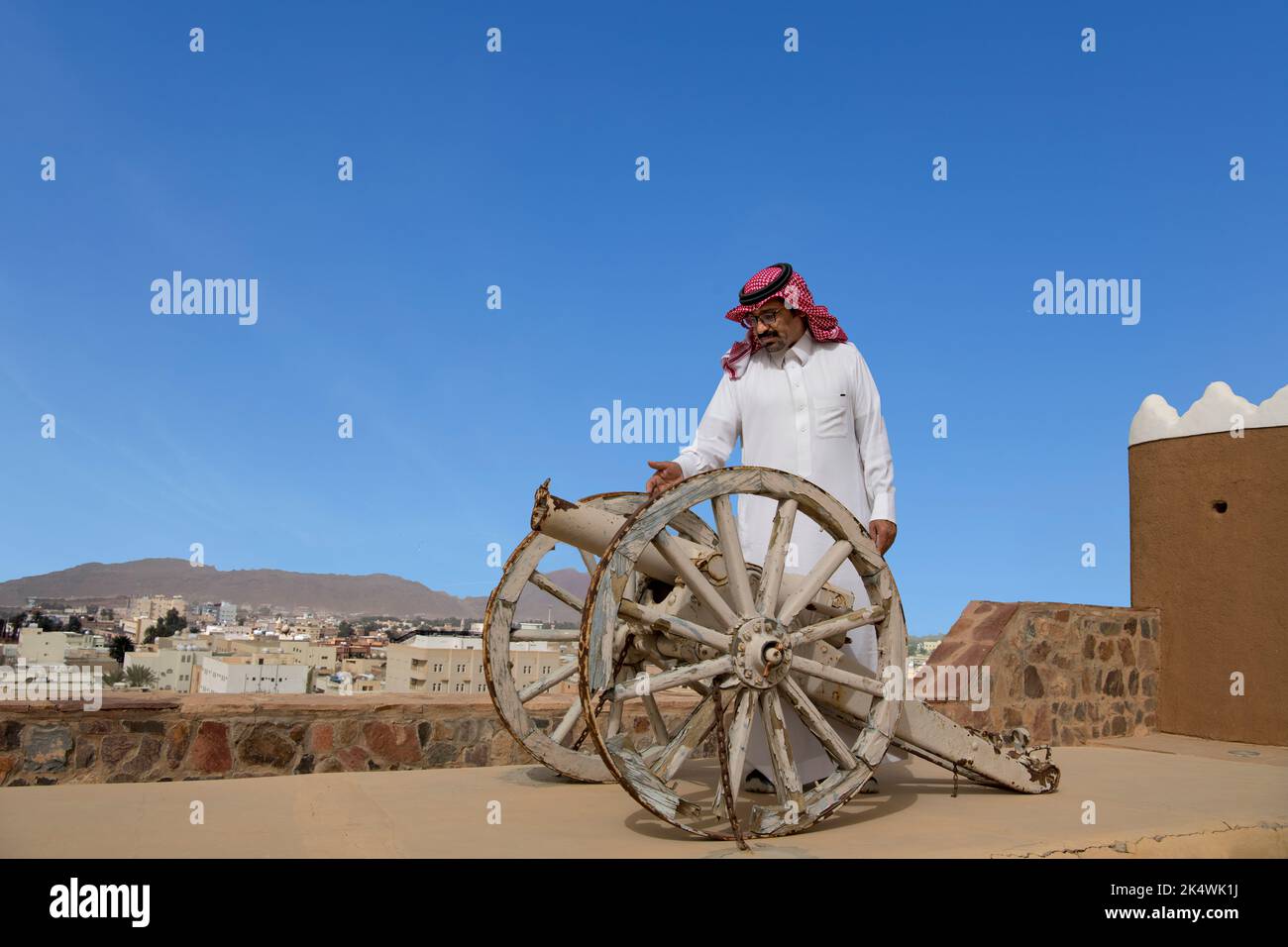 Hombre árabe inspeccionando el viejo canon en La parte superior del techo del fuerte A'Arif Ave Arabia Saudita Foto de stock