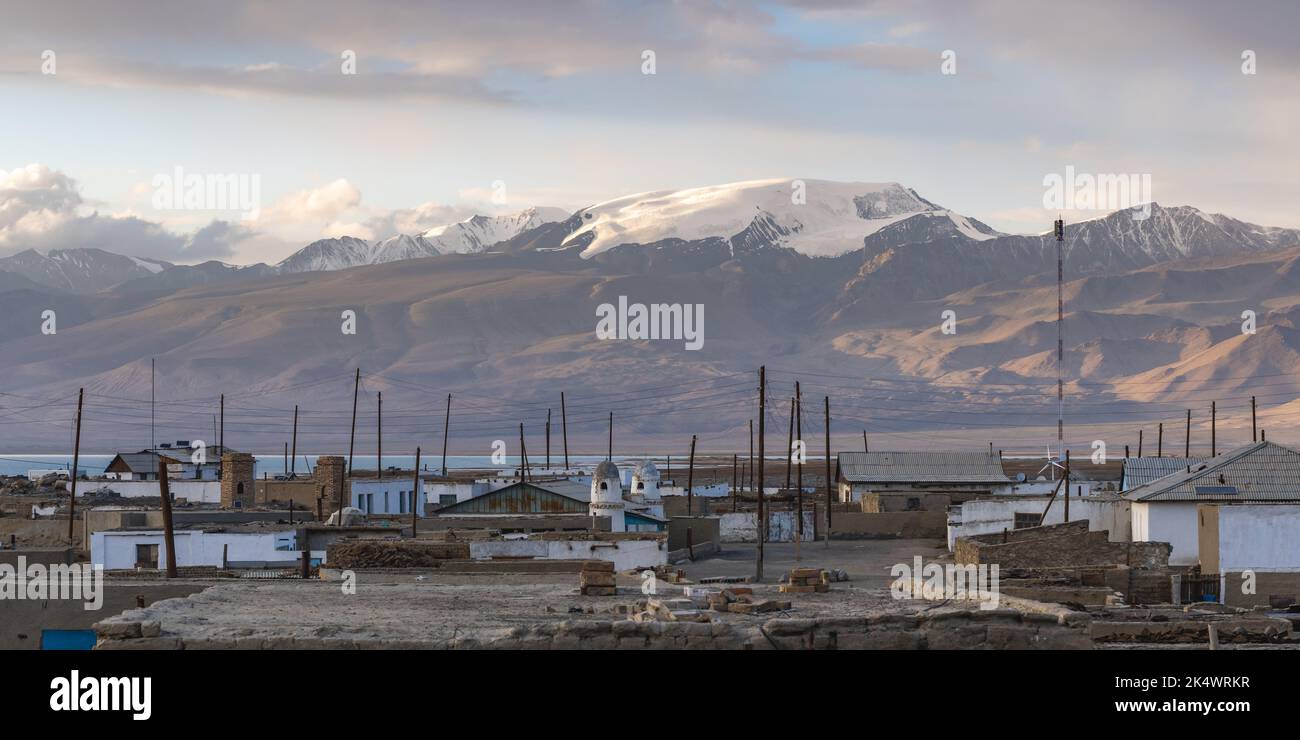 Vista de la puesta del sol de la aldea de Karakul a orillas del lago de Karakul con montañas cubiertas de nieve, distrito de Murghab, región de Gorno-Badakshan Pamir en Tayikistán Foto de stock