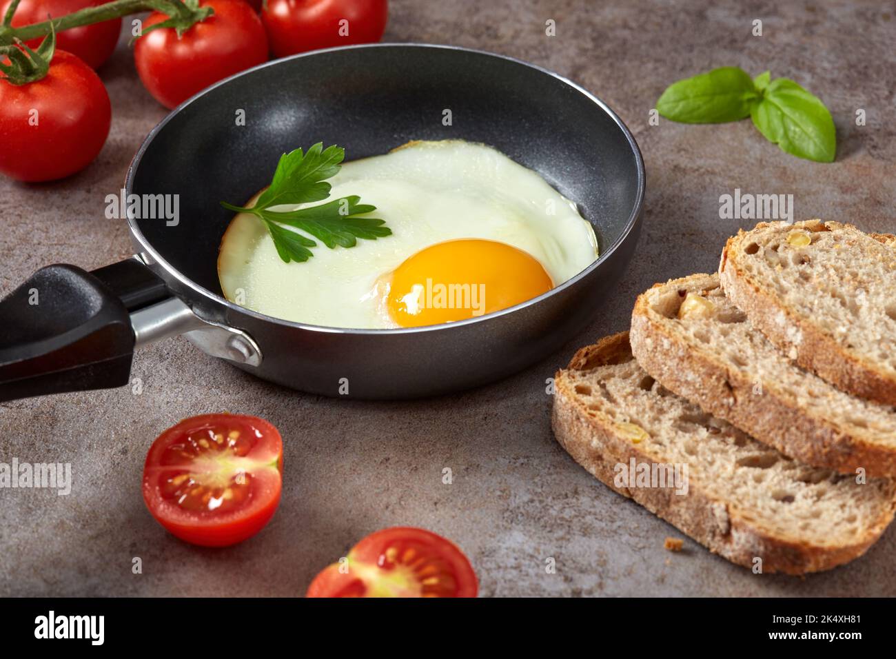 Pequeña sartén con un huevo frito, pan y tomates cherry - primer plano Foto de stock