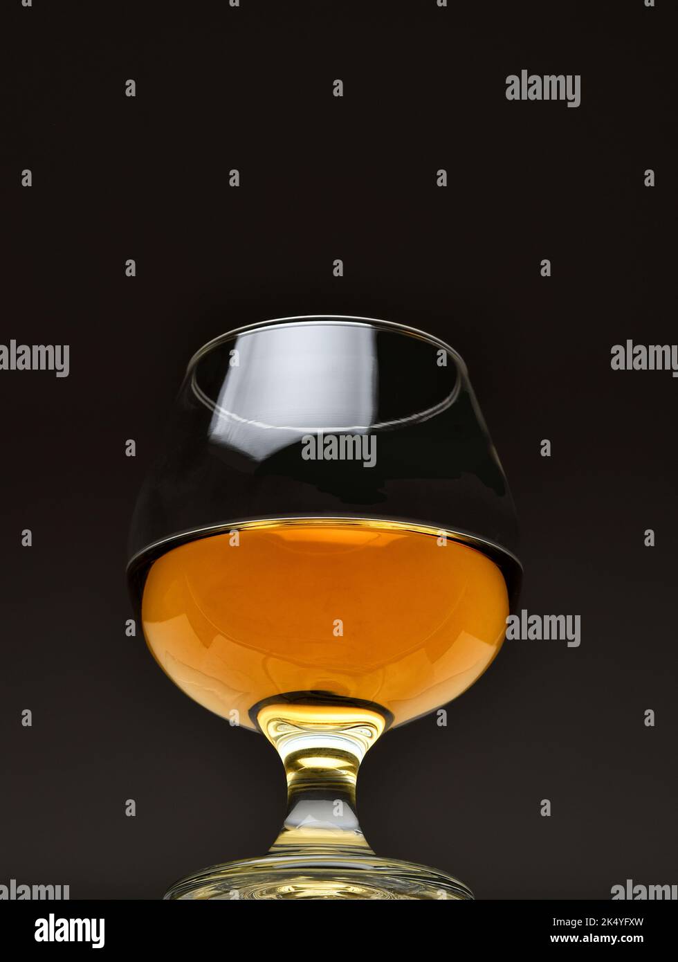 Snifter brandy visto para un ángulo bajo sobre un fondo oscuro. Foto de stock