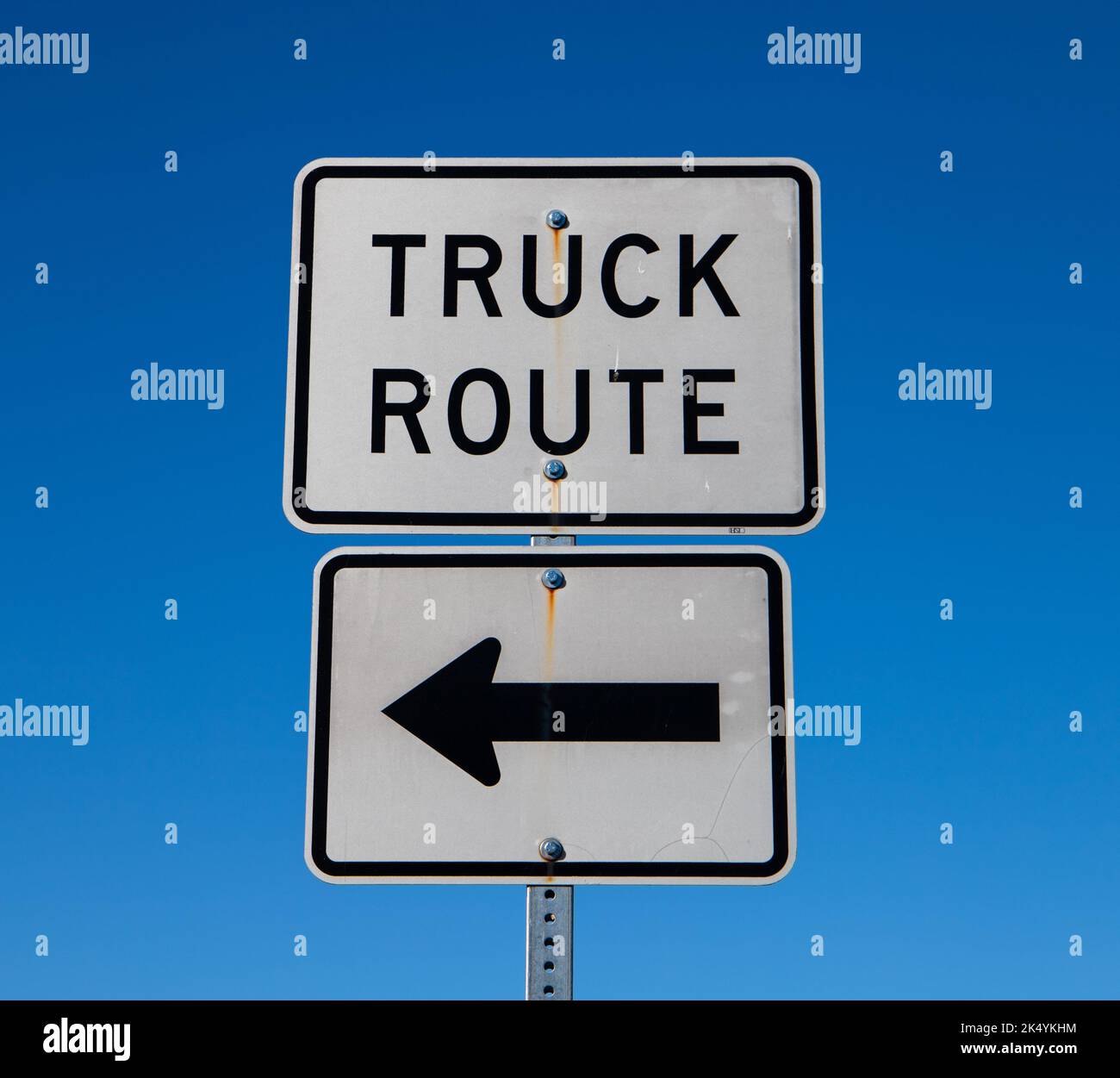 Señal de ruta para camiones con una flecha apuntando a la izquierda y un fondo azul brillante del cielo Foto de stock