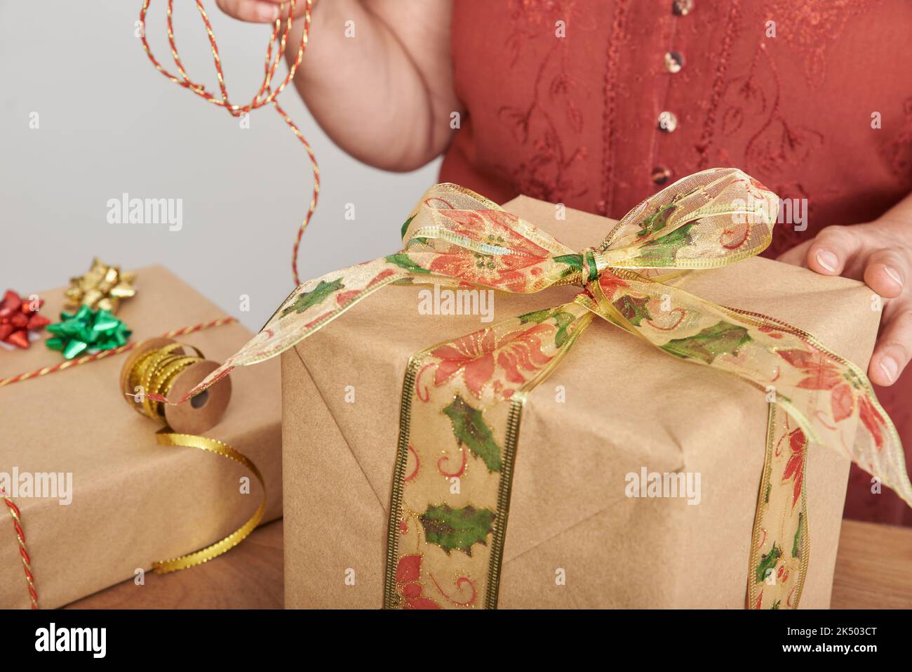 Mujer madura irreconocible envolver regalos de Navidad en casa con papel  neutro y cintas y cordones decorativos Fotografía de stock - Alamy