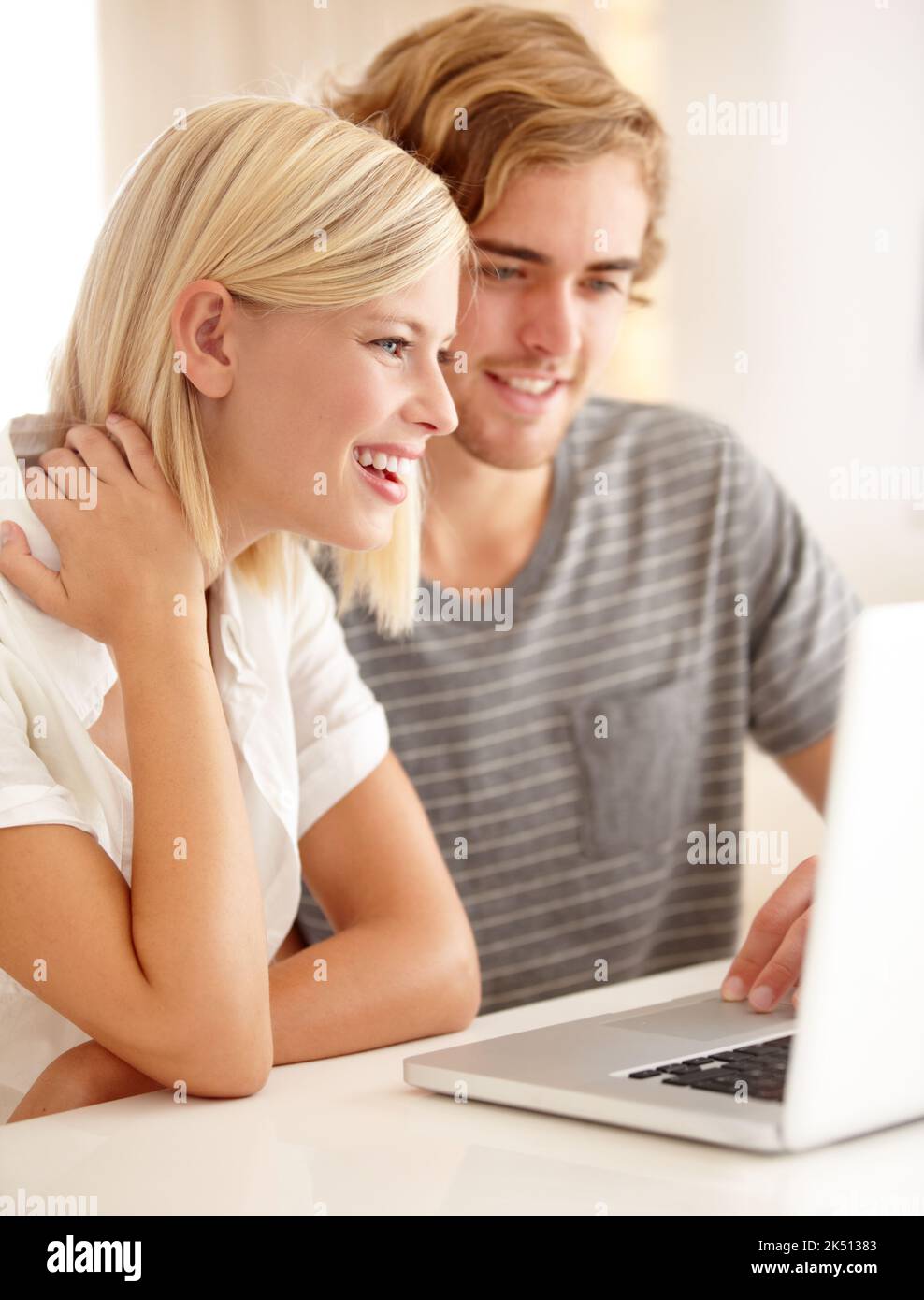 Reírse de un correo electrónico divertido Una pareja joven que usa un ordenador portátil para navegar por la web. Foto de stock