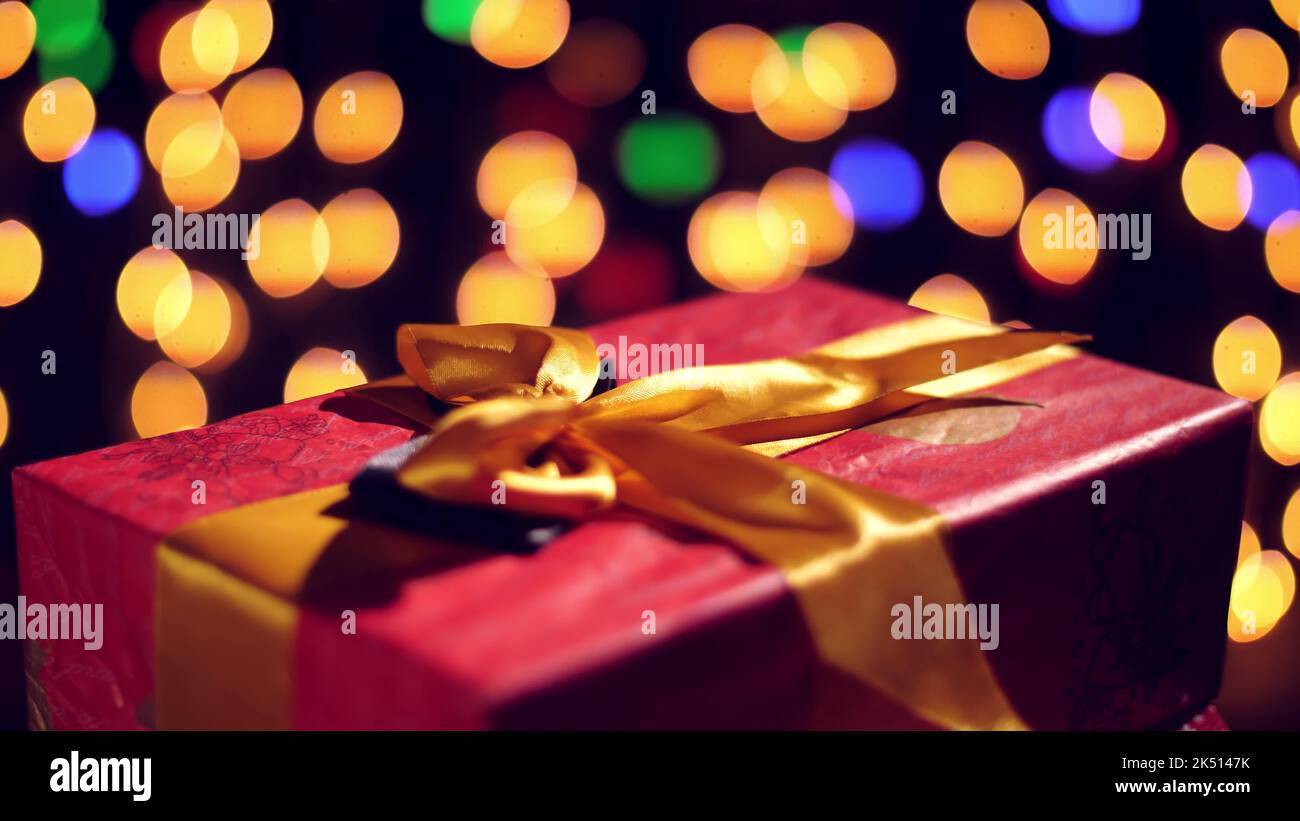 regalos bellamente envueltos con cintas rosadas. regalos sobre luces bokeh o guirnaldas brillantes de fondo. primer plano, rotación. Navidad o Año Nuevo. Concepto de caridad. Ambiente festivo. Fotografía de alta calidad Foto de stock