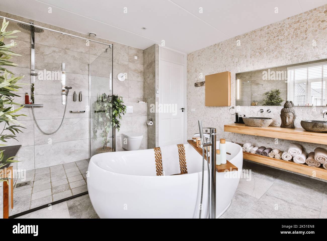 Interior de un baño moderno con decoración asiática, suelos de mármol y  bañera ovalada blanca junto a la cabina de ducha Fotografía de stock - Alamy