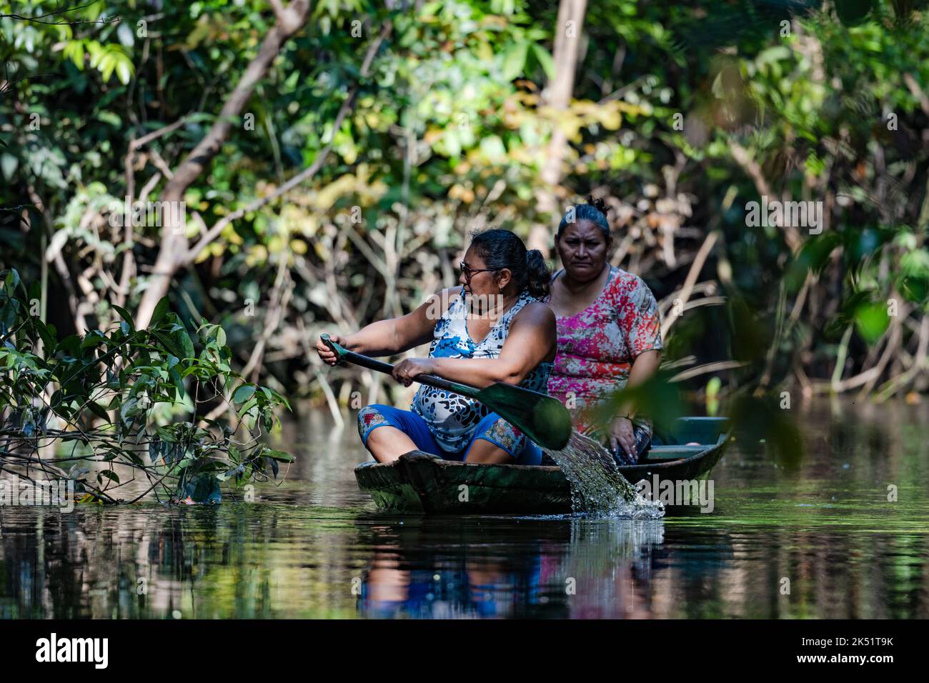 Dos indígenas pescando en un barco en el bosque de várzea. Amazonas, Brasil. Foto de stock