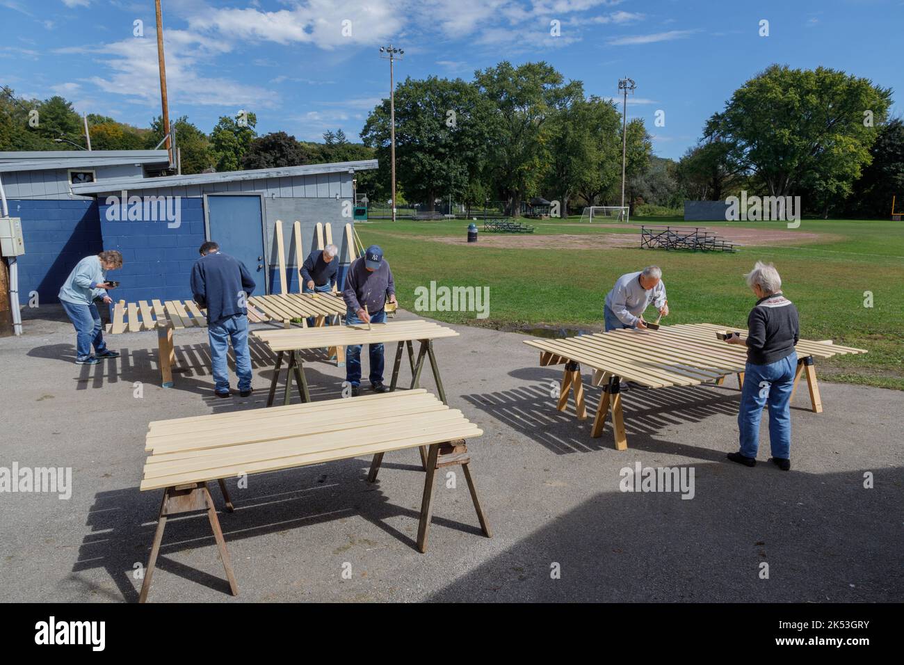 St. Johnsville, Montgomery County, Nueva York: Los voluntarios pintan tablillas de madera durante la reparación de la tribuna en el campo de pelota de la comunidad. Foto de stock