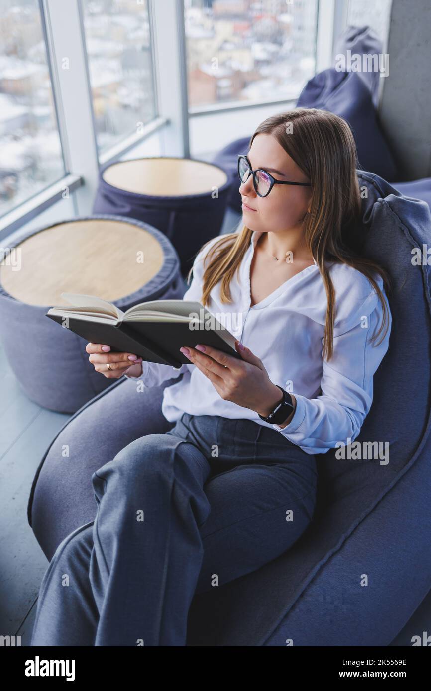 Descanso. Mujer joven sonriente en vasos relajándose en una silla de bolsa  de frijoles sentada en la mesa y relajándose usando el bloc de notas, mujer  feliz recostándose disfrutando del trabajo f