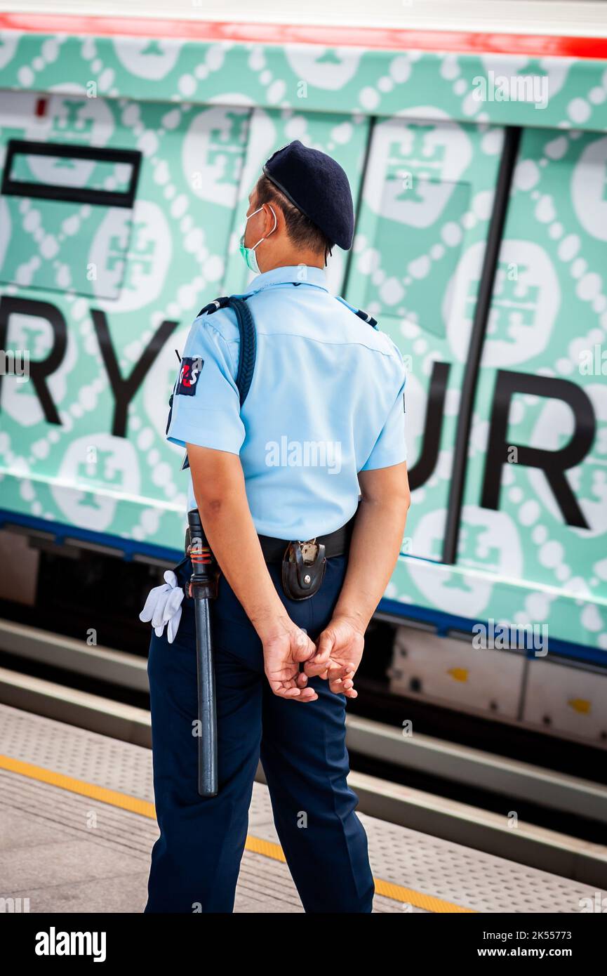 Un guardia de tren tailandés inteligente observa al público y entrena en la plataforma de una estación de tren aéreo BTS de Bangkok. Foto de stock