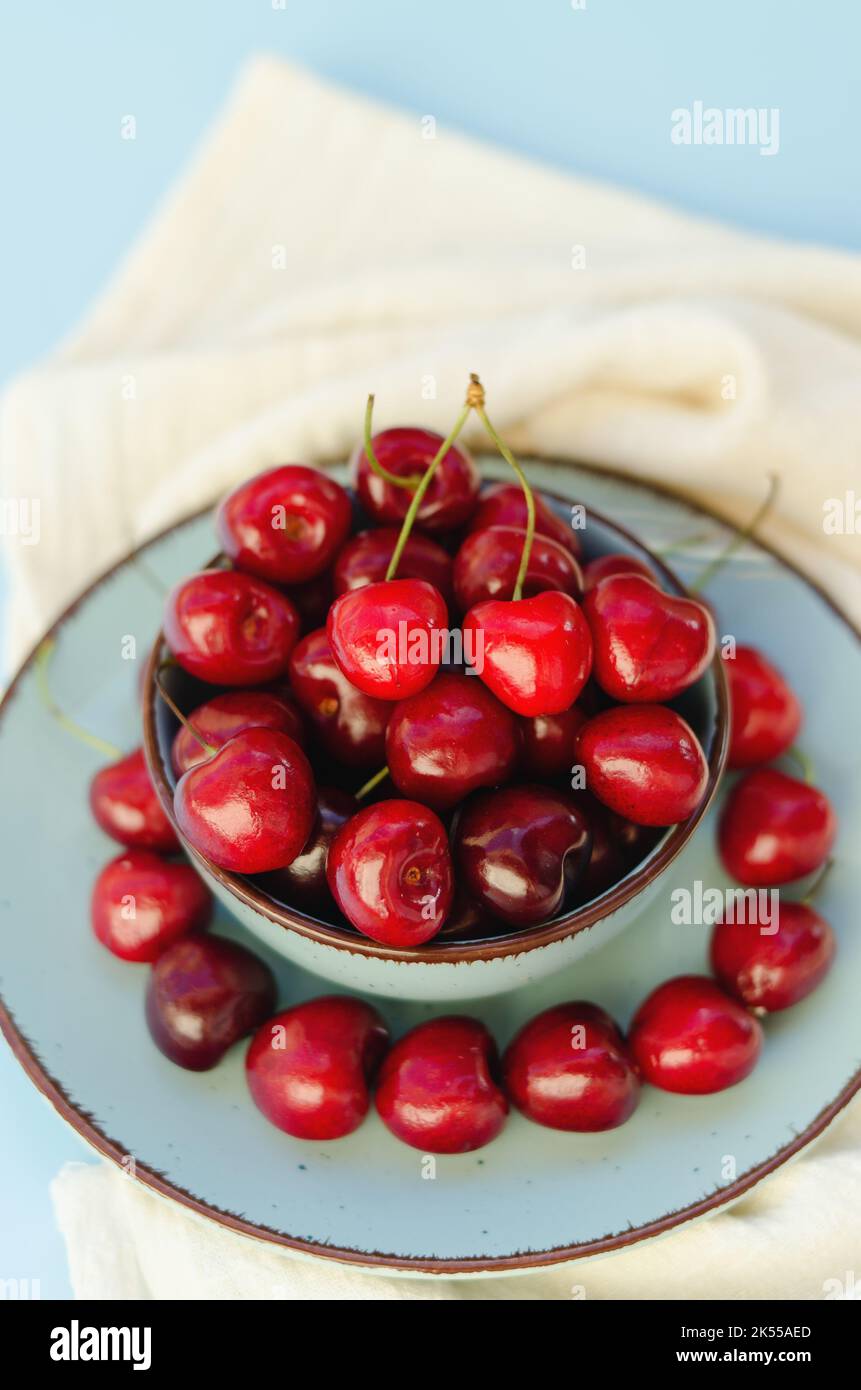Vista superior de cereza dulce roja sobre placa azul de cerca. Vegano, concepto de comida de verano. Concepto de dieta saludable Foto de stock
