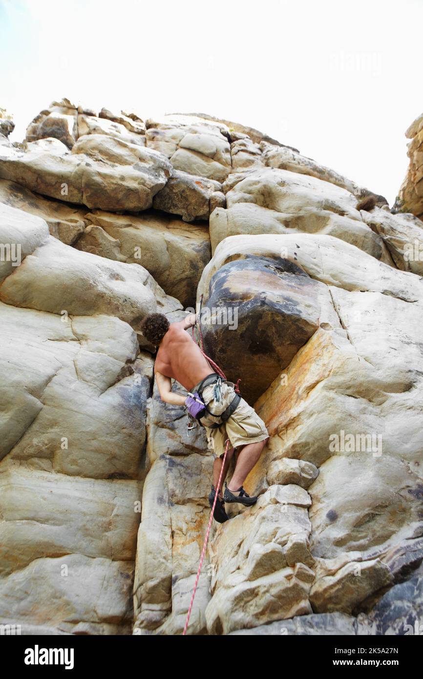 Aferrarse a la vida querida. Un escalador colgando en la cara del acantilado. Foto de stock