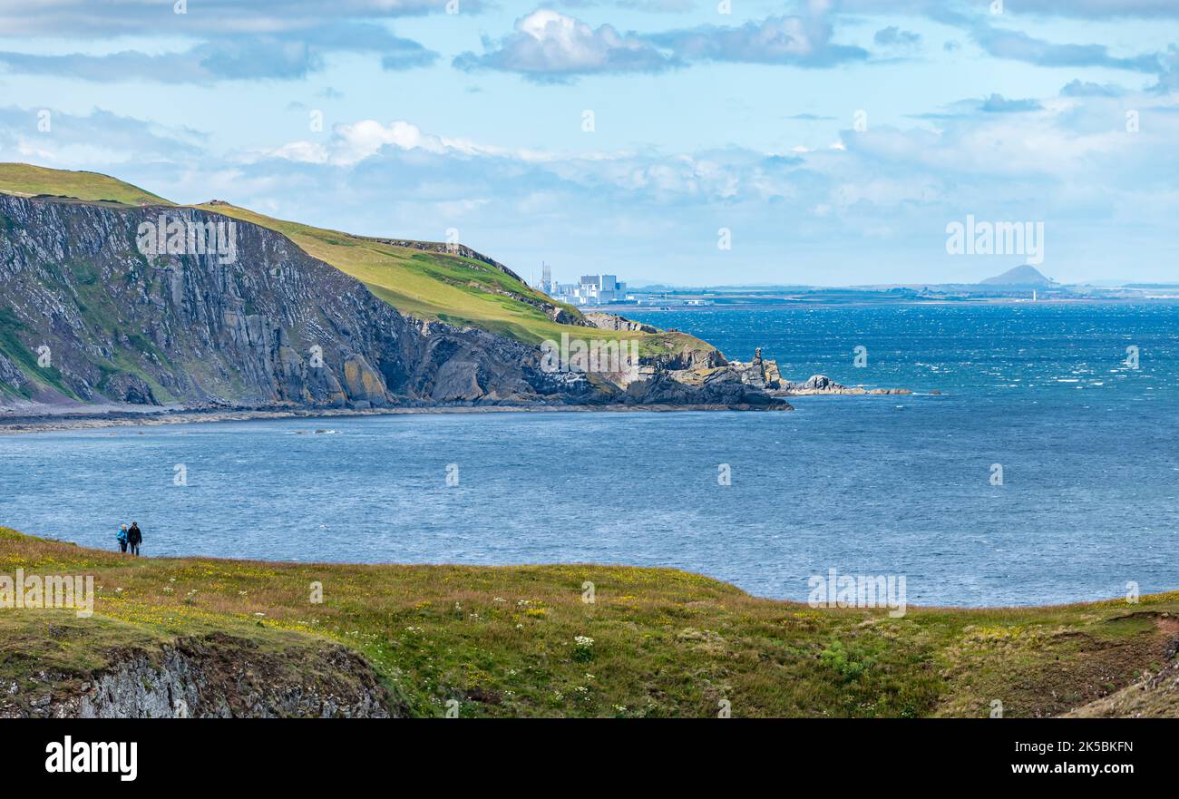 Vista de la costa rocosa con la central nuclear de Torness y Berwick Law en la distancia, Escocia, Reino Unido Foto de stock