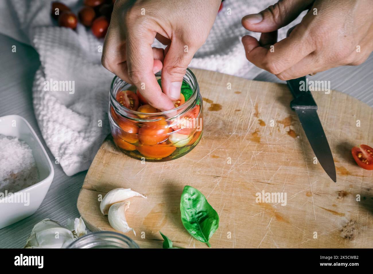 preparación casera, tomates en aceite con ajo, albahaca Foto de stock