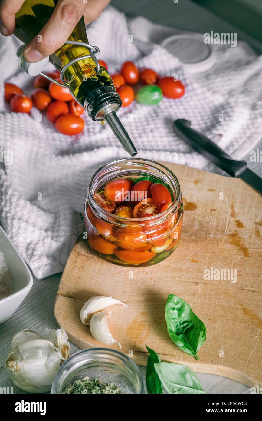 preparación casera, tomates en aceite con ajo, albahaca Foto de stock