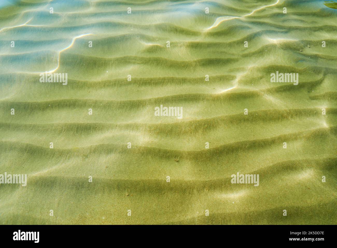 Ondas y resplandor en el agua del mar y olas en la arena bajo el agua. Naturaleza abstracta y fondos tropicales Foto de stock