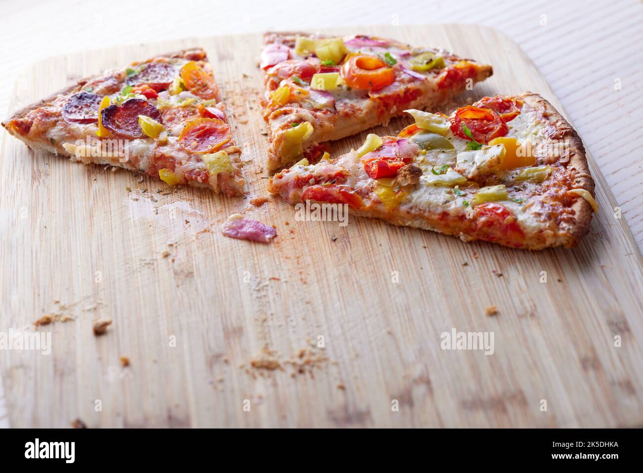 Pizza con salami, pimientos de pepperoni, tomates y cebollas en una mesa con espacio para copias Foto de stock