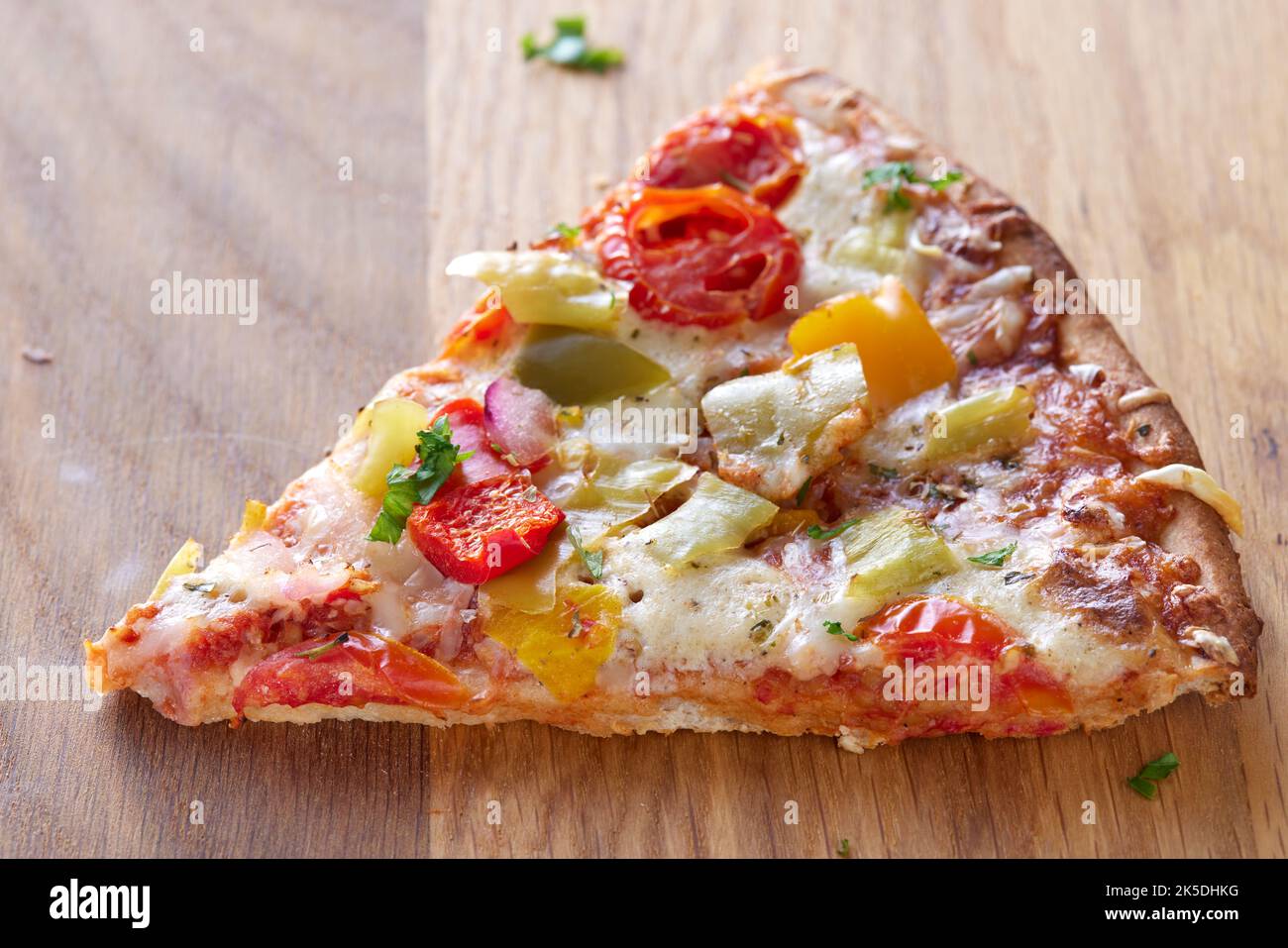 Una porción de pizza con salami, pimientos de pepperoni, tomates y cebollas. Vista de primer plano Foto de stock