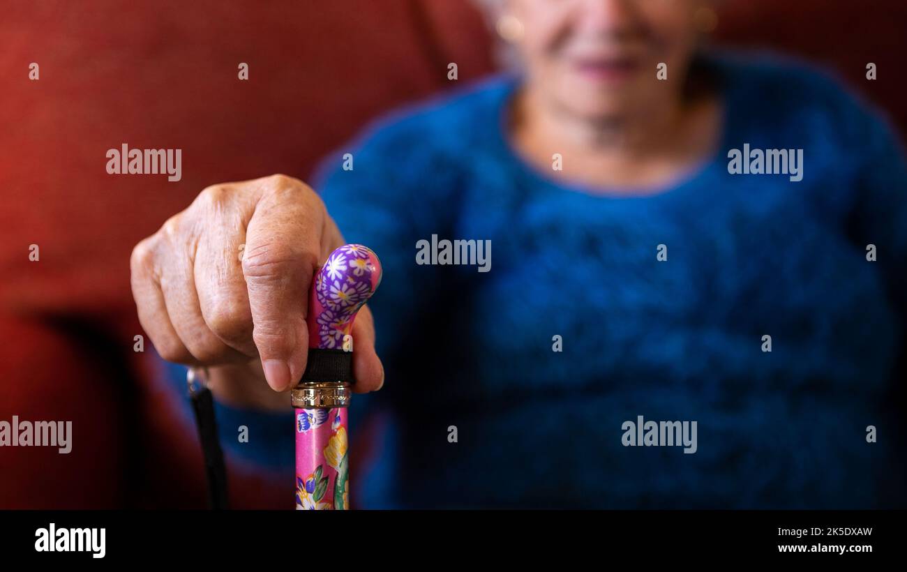 Primer plano de las manos de la mujer mayor sosteniendo el bastón. Detalle de la vieja manilla de la abuela caucásica de caña. Concepto de personas mayores. Foto de stock