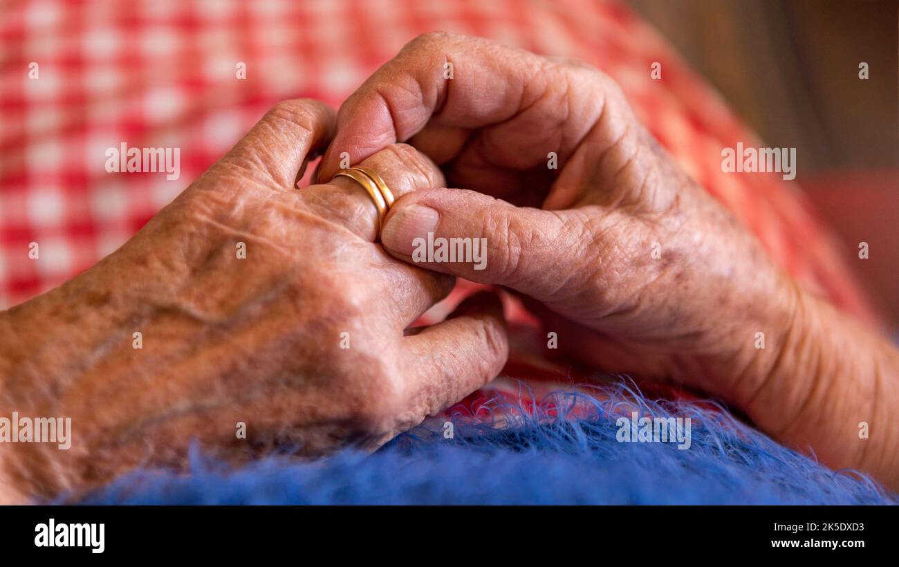 Acérquese a las manos de una anciana viuda con anillos. Abuela caucásica sentada en casa. Manos arrugadas de la abuela de 93th años Foto de stock