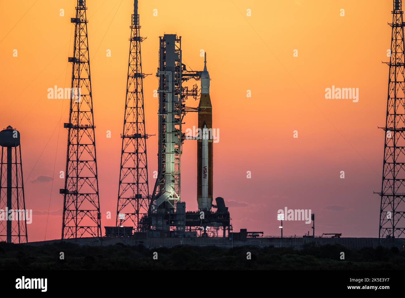 Artemis I en la Pad. Sunrise proyecta un cálido resplandor alrededor del Sistema de Lanzamiento Espacial Artemis I (SLS) y la nave espacial Orion en Launch Pad 39B en el Centro Espacial Kennedy de la NASA en Florida el 21 de marzo de 2022. El SLS y Orion encima del lanzador móvil fueron transportados a la plataforma en Crawler-Transporter 2 para una prueba de prelanzamiento llamada ensayo de vestido mojado. Artemis I será la primera prueba integrada de la nave espacial SLS y Orion. Crédito de la imagen: NASA/BSmegelsky Foto de stock