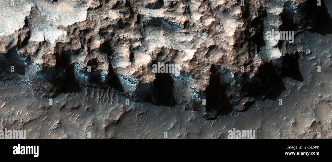 Paisaje marciano. Esta imagen de HiRISE muestra hielo en un acantilado con clorito en el noroeste de Hellas. Una escarpa orientada al sur en la región noroeste de Hellas que fue blanco de filosilicatos (esto incluye minerales arcillosos) muestra instancias de roca azulada en esta imagen en color realzada. Los espectros de CRIM del material azulado muestran que consiste en una combinación de clorito y hielo de agua. La imagen en color realzada es inferior a 1 km (menos de una milla), una versión optimizada única de las imágenes de la NASA. Crédito: NASA/JPL/UArizona Foto de stock