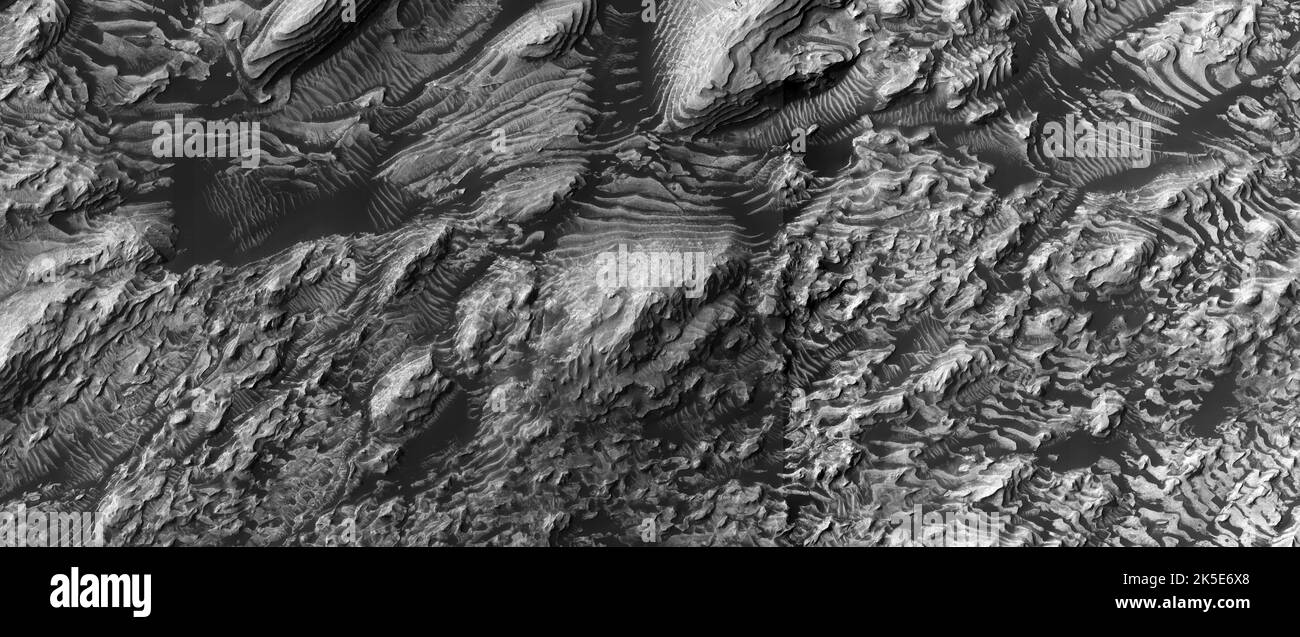 Paisaje marciano. Esta imagen de HiRISE muestra formas terrestres en la superficie de Marte. Afloramientos de rocas en capas en el cráter Danielson, Marte. La arena oscura descansa entre los afloramientos. Danielson tiene unos 68km mm de diámetro y está al norte de Meridiani Planum. Las capas en el piso de Danielson pueden haber sido formadas en el fondo de los lagos. La imagen muestra un terreno a menos de 5 km (menos de 3 mi) a través De Una versión optimizada única de las imágenes de la NASA. Crédito: NASA/JPL/UArizona Foto de stock